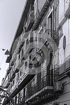 Old building with bars on the balconies sunset and trees around it in black and white photo