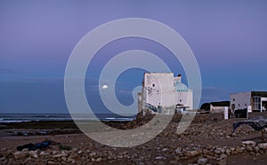 Old building at coast of Sidi Kaouki, Morocco, Africa. Moon in the evening sky. Sunset time. morocco`s wonderfull surf to