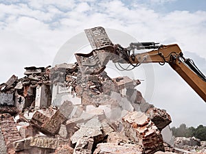 Old building demolition. Excavator working in rubble.