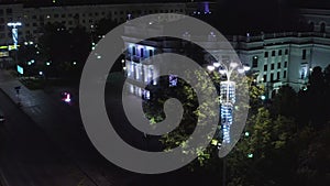 Old building illuminated by lanterns in modern night city. Stock footage. Top view of lighted old building in center of