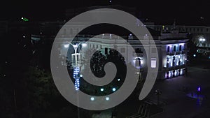 Old building illuminated by lanterns in modern night city. Stock footage. Top view of lighted old building in center of