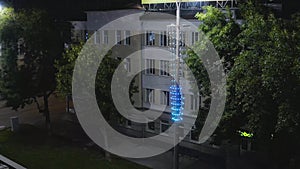 Old building illuminated by lanterns in modern night city. Stock footage. Top view of lighted old building in center of