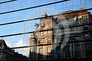 An Old Building On A New Building Reflection.