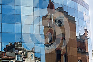 Old building is reflected in the windows of the facade