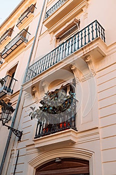 Old building wall in the streets of the city of Valencia. Windows and balconies decorated with evergreen plants.Spain.