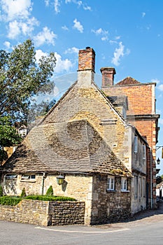 Old buildings in an English village with multiple chimneys under a pretty blue cloudy sky