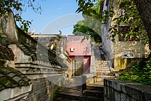 Old buildings by stone stairway on slope in sunny morning