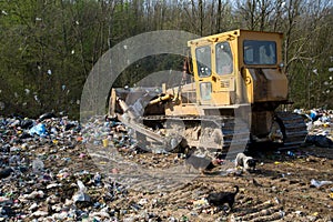 The old bulldozer moving garbage in a landfill