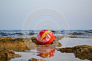 Old buoy of red color, thrown ashore