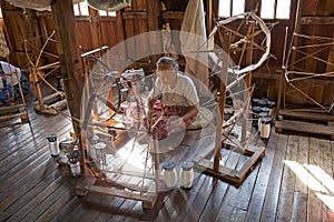 Old burmese woman is spinnig a lotus thread