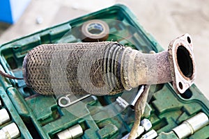 Old burnt corrugation muffler on set of tools photo