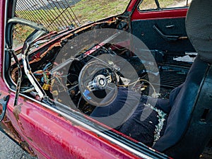 An old burnt-out red car in close-up. The concept of danger and disaster