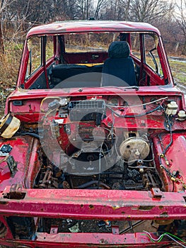 An old burnt-out red car in close-up. The concept of danger and disaster