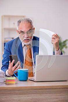 Old businessman employee sitting in the office