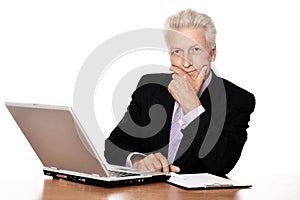 Old businessman in headphones working with laptop isolated on white background