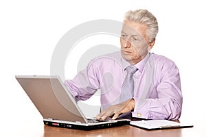 Old businessman working with laptop isolated on white background