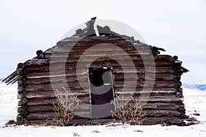 Old cabin leaning in the winter snow