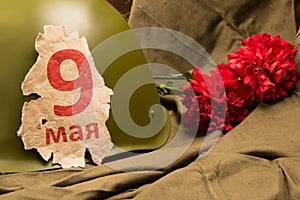 Old calendar page 9 may, about a military helmet and two red carnations on a background of raincoat tent