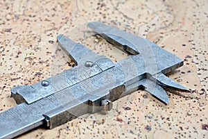 Old calipers on cork background. Vintage measuring tool