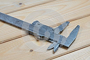 Old calipers on wooden background. Vintage measuring tool