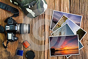 Old camera, cap, memory cards and stack of photos on vintage wooden background