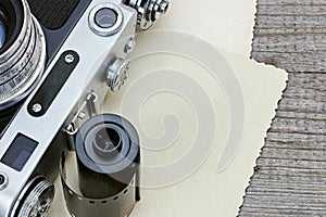 old camera, film roll and aged pictures on gray wooden table closeup