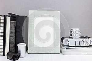Old camera, notebooks, photo frame, roll film on grey background