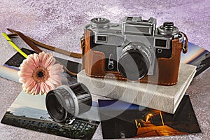 Old camera, old lens, color photos, photo album and gerbera flower on the table. World Photography Day, August 19