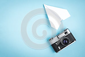 Old camera and paper plane on blue background