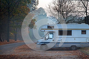 Old camper van parked in next to the road on foggy and cold autumn morning