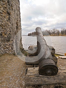Old cannon that defended medieval fortification on the shore of river. Old ruined castle and its weapons.