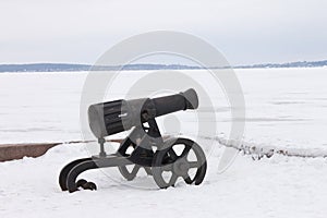 Old cannon on a winter snow-covered embankment