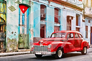 Old car and and building with the cuban flag in Old Havana