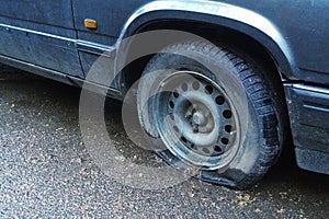 Old car with flat tyre on the street, closeup