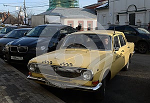 The old car GAZ-24 `Volga` taxi yellow is on the street Varvarka in Moscow.