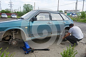The old car is lifted up. Removing the wheels from the machine for replacement.