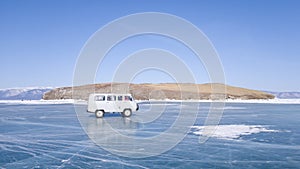 The old car moves on the ice of lake Baikal during the tour. A winter journey in Russia