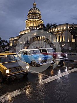 Old car on streets of Havana with Capitolio building in background with reflection on rain time. Cuba