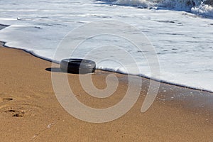 Old car tires on the beach,Water and sea coast pollution car tires on sand beach,An image of an old car tire ingrown into the sand