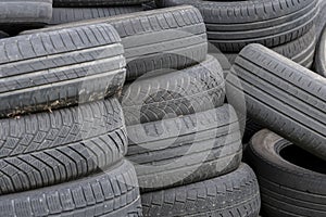 Old car tires, worn tread, worn rubber, a pile of old car wheels, a dump of worn tires from used cars. Environmental pollution