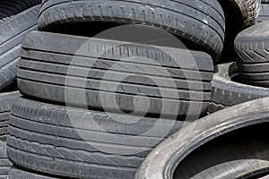 Old car tires, worn tread, worn rubber, a pile of old car wheels, a dump of worn tires from used cars. Environmental pollution