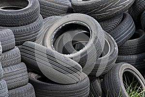 Old car tires, worn tread, worn rubber, a pile of old car wheels, a dump of worn tires from used cars. Environmental pollution