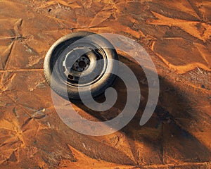 Old car wheel on weathered rusty metal sheet.