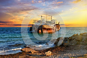 Old cargo ship is aground on the Black Sea coast at sunset in Crimea, Ukraine