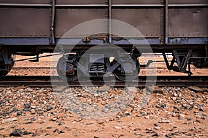 Old cargo train at Wadi Rum desert station, red sand and dust near railroad tracks, closeup detail from side