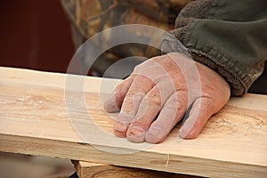 The old carpenter checks the quality of the sanding of the wood. A man`s hand strokes a wooden board. Making wooden furniture con