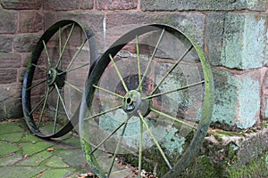 Old cart wheels rusting propped up against a wall