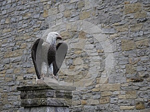 Old carved stone eagle sculpture on pillar by wall. With copyspace.