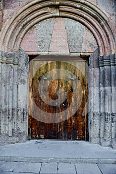 Old carved wooden church door with hinges.