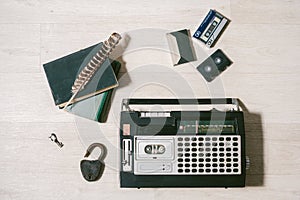 Old cassette tape recorder, key, lock, books and feather on wood